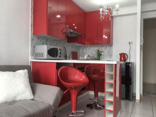 圣地亚哥Depto Metro Cal y Canto的一间设有红色橱柜和红色凳子的小厨房