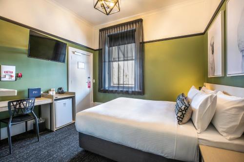 Port AdelaideNightcap at Exeter Hotel的配有一张床和一张书桌的酒店客房