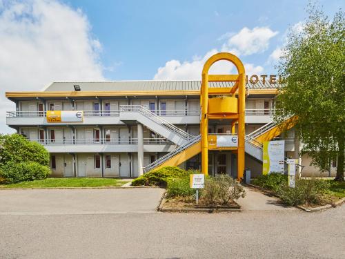 维尔特·圣丹尼斯Première Classe Melun Senart的一座办公室大楼,前面有一个黄色螺旋楼梯