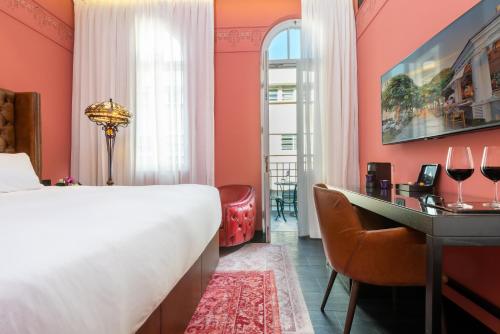 特拉维夫Bachar House的一间卧室设有橙色的墙壁、一张床和一张书桌
