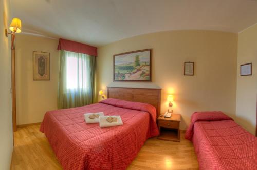 佩斯卡塞罗利Hotel Garnì Posta的酒店客房,配有两张带红色床单的床