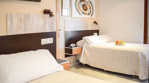 格拉纳达阿尔贝罗酒店的一间卧室配有两张床和镜子
