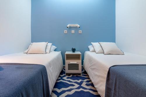 圣巴托洛梅Flatguest Villa Yaiza PISCINA EN REFORMAS的蓝色墙壁客房的两张床