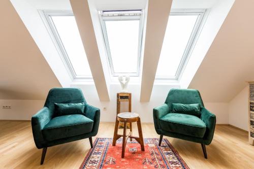 格拉茨Große Dachgeschosswohnung im Herzen von Graz的带窗户的客房内的两张绿色椅子和一张桌子