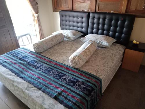 班图尔JOGLOPARI GuestHouse bukan untuk pasangan non pasutri的一张带黑色床头板和枕头的床
