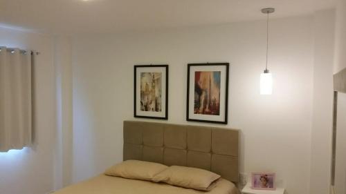 普拉亚多AP. DE LUXO NO IBEROSTATE的卧室配有两张墙上的照片和一张床