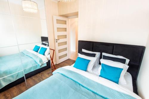 波兹南Super-Apartamenty Targi Poznańskie的一间卧室配有两张带蓝白色枕头的床