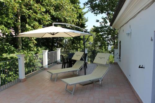 MontescudoCasa Ugolini since 1857的庭院配有椅子、遮阳伞和桌子。
