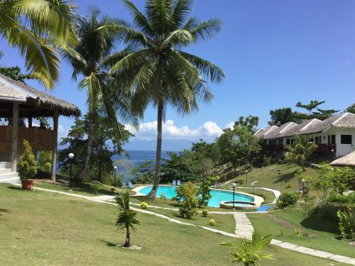 巴迪安Cuestas Beach Resort and Restaurant的享有带游泳池和棕榈树的度假村景色