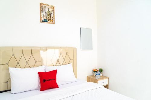 雅加达RedDoorz near Tarumanagara University的卧室配有带红色枕头的白色床