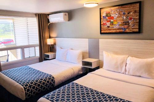 魁北克市Hotel Motel Le Regent的酒店客房设有两张床和窗户。