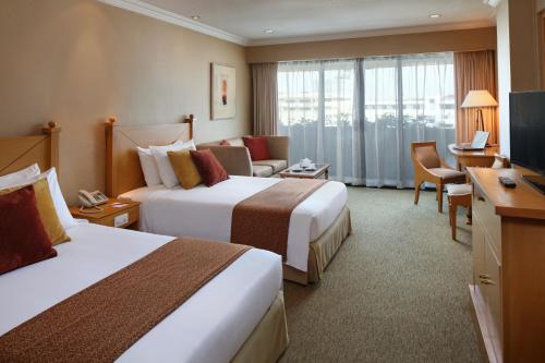 马尼拉The Heritage Hotel Manila的酒店客房设有两张床和电视。