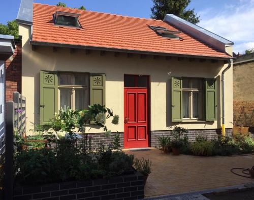 波茨坦Ferienwohnung Kamp `Himmelsblick` mit Schlafgalerie的一座带橙色屋顶和红色门的小房子