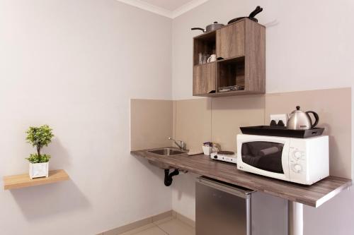 比勒陀利亚Menlyn Apartments的厨房配有带微波炉和水槽的台面