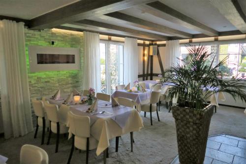 奥弗拉特Landhotel Bergischer Hof GmbH Marialinden的一间设有白色桌椅的用餐室