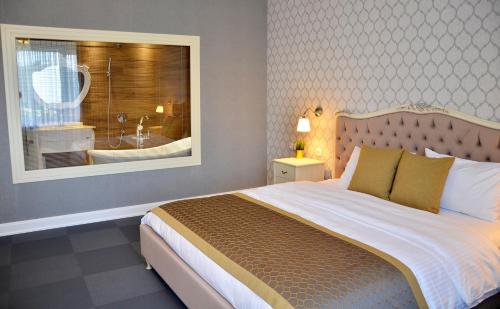 莫姆奇尔格勒Hotel Konak的一间卧室设有一张大床和一个带浴缸的窗户。