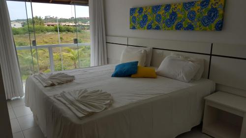 塞古罗港Condomínio Mar da Galiléia - Apto 27的一张带两个枕头的白色床和窗户
