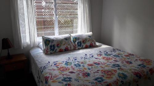 拉罗汤加Te Akapuao Studio Villas的一张带花卉床罩的床铺,配有窗户