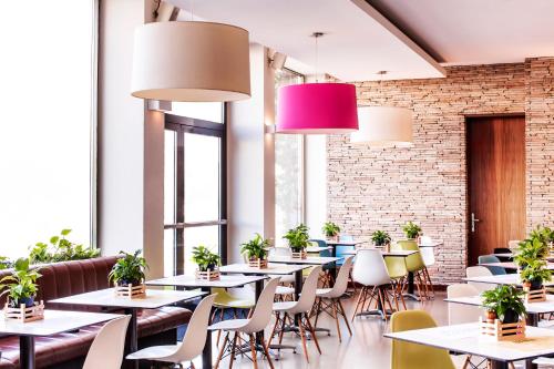 格拉茨Hotel Daniel Graz - Smart Luxury Near City Centre的一间设有桌椅和盆栽的餐厅