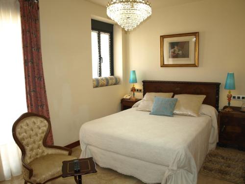 Ventosa拉斯哥达斯乡村旅馆的一间卧室配有一张床、一把椅子和一个吊灯。