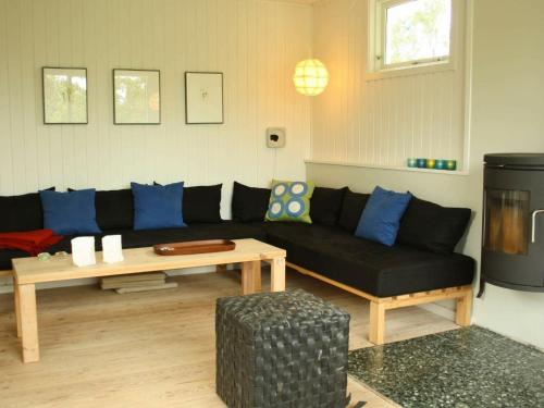Hornsved4 person holiday home in J gerspris的客厅配有黑色沙发和桌子