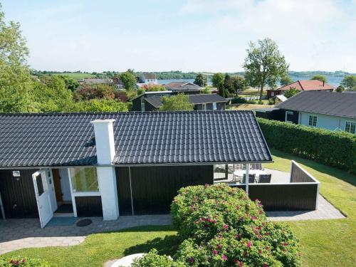 布罗艾厄4 person holiday home in Broager的黑色屋顶和灌木的房子