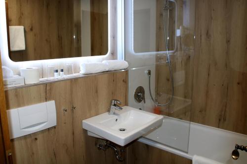瓦尔拉夫施万祖姆诺恩酒店的一间带水槽、淋浴和镜子的浴室