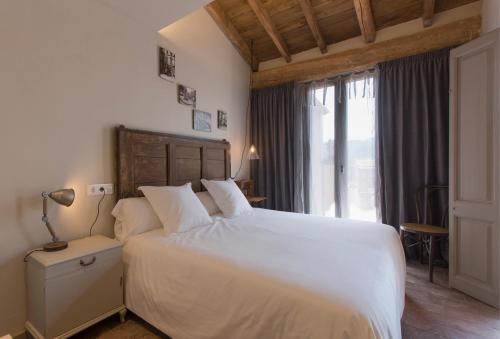 奥洛特El Jardinet de Sant Esteve的卧室设有白色的床和大窗户