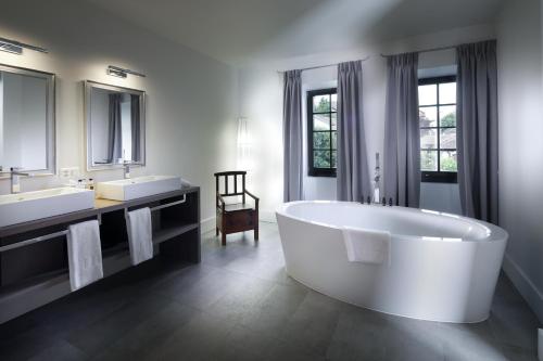 LucensLa Ferme du Château的大型浴室设有大浴缸和两个水槽