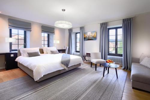 LucensLa Ferme du Château的卧室配有一张白色的大床和一张沙发。