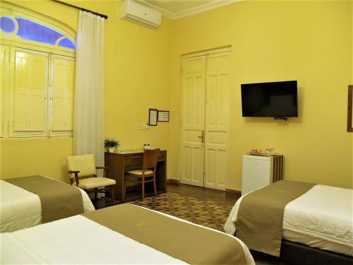 亚松森德尔巴拉圭格兰酒店的酒店客房设有两张床、一张桌子和一台电视。
