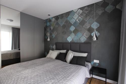 济夫努夫Apartament Gardenia Sea&Sun DZIWNÓW PRZY PLAŻY的卧室配有白色的床和灰色的墙壁