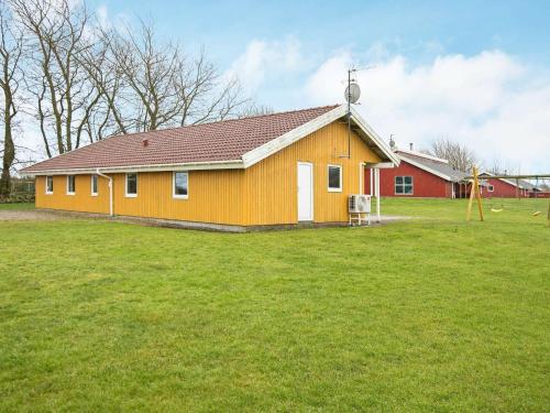 诺德堡12 person holiday home in Nordborg的草场上的一个小黄房子