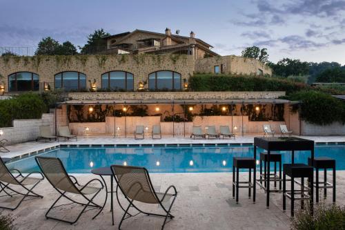 奥维多Altarocca Wine Resort Adults Only的一个带椅子和桌子的庭院,毗邻一个游泳池