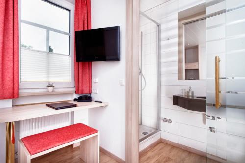 罗滕堡古登斯范斯TOP酒店的一间带红色长凳和电视的小浴室