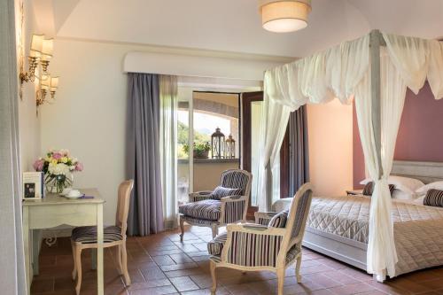 奥维多Altarocca Wine Resort Adults Only的一间卧室配有天蓬床和桌椅