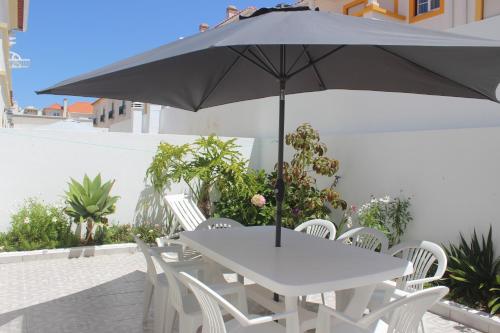 巴勒尔Baleal Holiday House的一张白色的桌子和椅子,配有雨伞