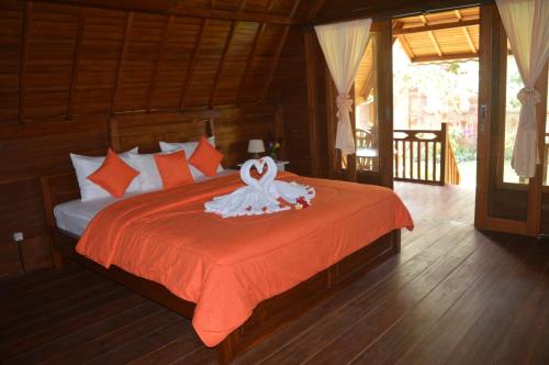 特贾库拉The Lumbung Tejakula的一间卧室配有一张带橙色毯子的床