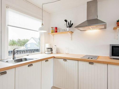 瓦伊厄斯斯特兰德4 person holiday home in Vejers Strand的厨房配有白色橱柜、水槽和窗户。