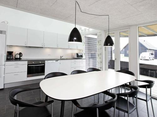 罗莫柯克比8 person holiday home in R m的厨房配有白色的桌子和黑色的椅子