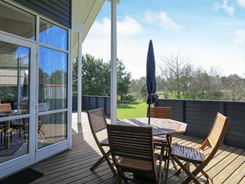 法贾德嘉德8 person holiday home in Ulfborg的庭院配有桌椅和遮阳伞。