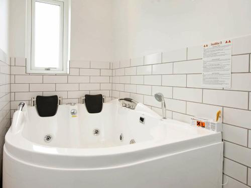 罗莫柯克比8 person holiday home in R m的白色浴室设有白色浴缸,浴室设有窗户