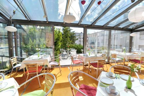 斯图加特阿巴理想酒店的餐厅设有白色的桌椅和窗户。