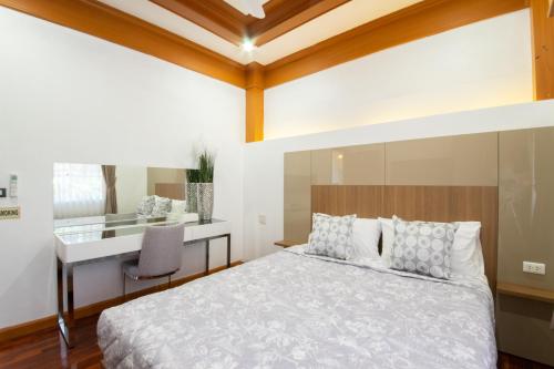 芭东海滩Rudi House的一间卧室配有一张床和一张书桌