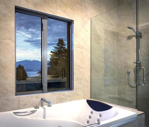 瓦纳卡高尔夫球场路度假屋旅馆的带淋浴和盥洗盆的浴室以及窗户。