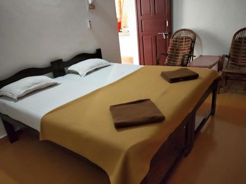 AguadaAlexmarie Guest house 5 min to candolim Beach的一张大床,位于带两把椅子的房间