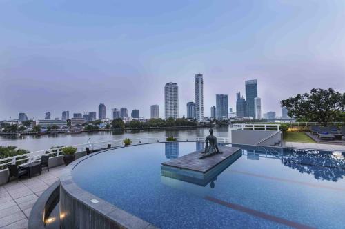 曼谷察殿曼谷河畔酒店的一座位于游泳池中间的雕像,享有城市天际线