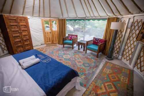 Roomy Yurts, Minapin Nagar Hunza的一间卧室配有一张床,帐篷内配有两把椅子
