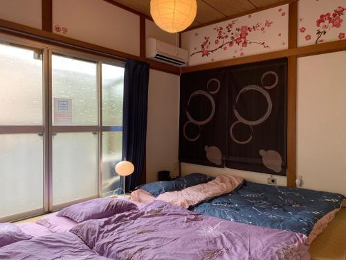 东京Kamata Ann的一间卧室配有一张带紫色床单的床和窗户。