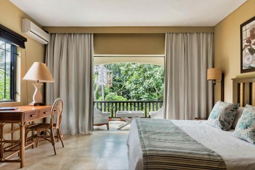 埃斯尼角Villa Vakoa - Tranquil Villa With Lush Gardens的配有一张床、一张书桌和一扇窗户的酒店客房